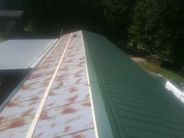 Old rusted panels beside newly installed green metal roofing — Wind Damage Roof Repair by Roofing Brothers in Worthington
