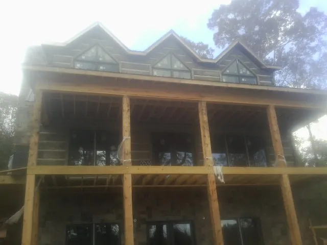 Dormers and porch framing on a large log home under construction — Roof Coating work by our crew in Worthington