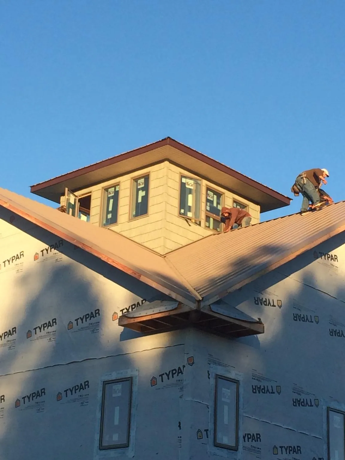 Roofers working around a rooftop cupola on a new metal roof at sunset — Roof Waterproofing in Worthington by Roofing Brothers